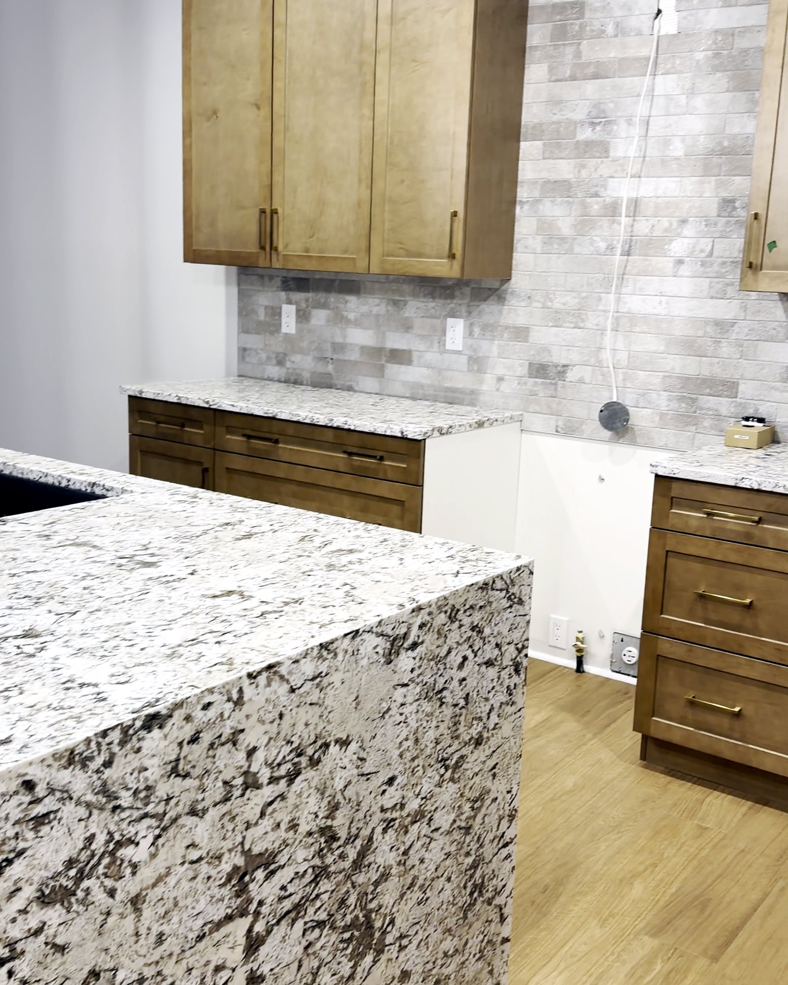 Finished kitchen island with granite top and clean pendant lights