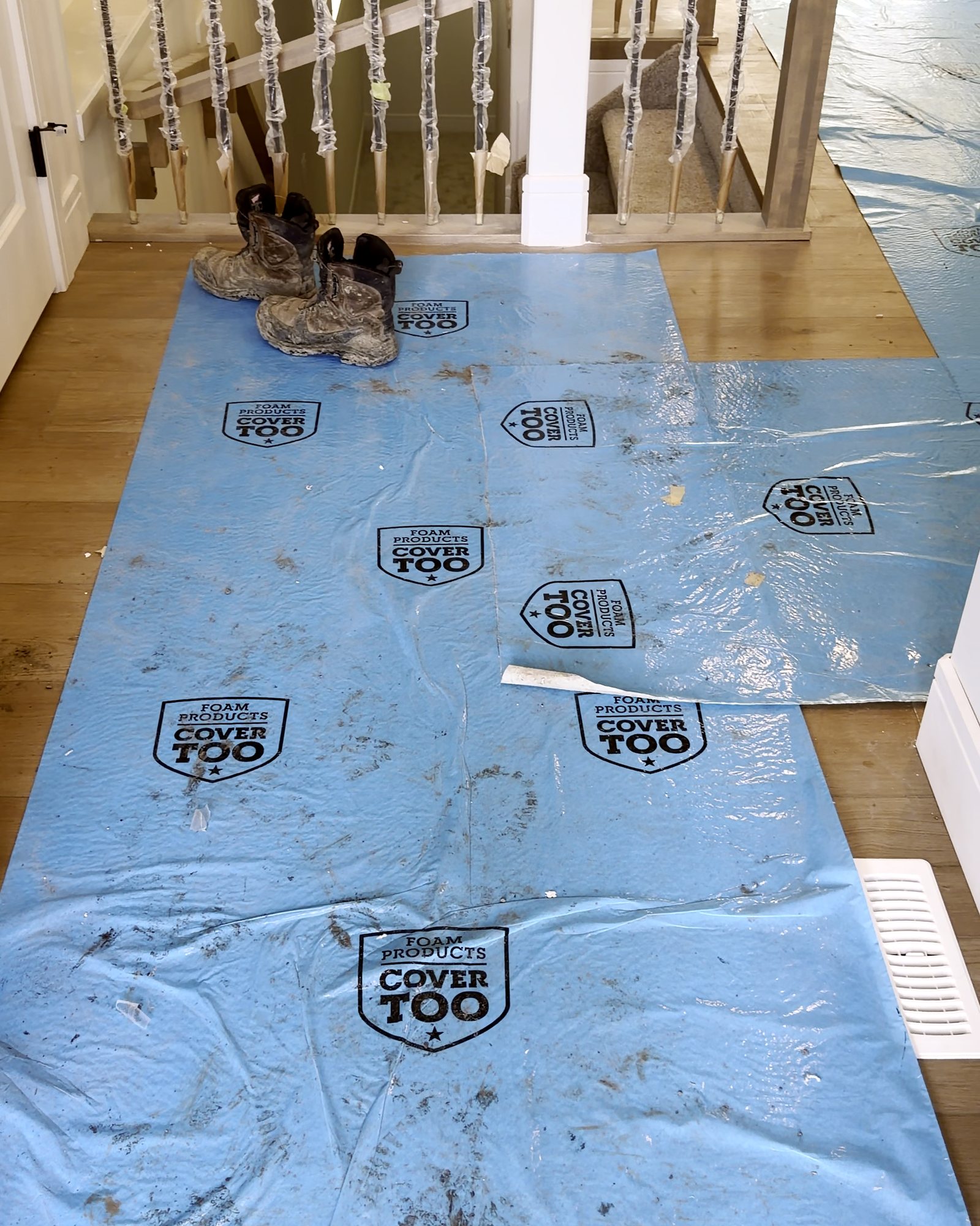 Hallway covered in blue floor protection with boot prints
