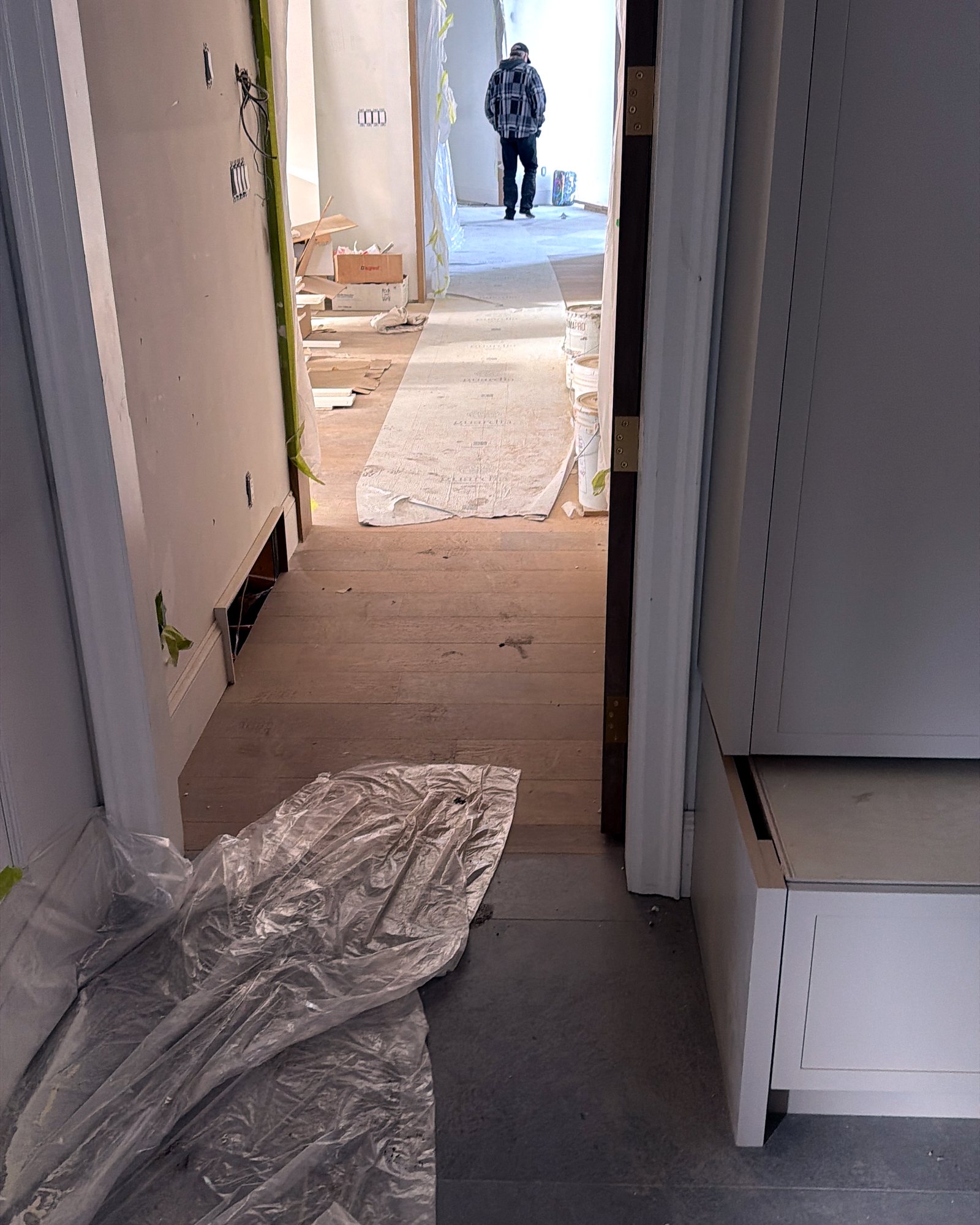 Hallway during construction with plastic sheeting and debris on the floor